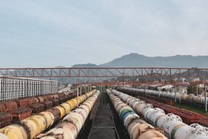 Aerial view of cargo trains lined up at a large railway yard under a blue sky.