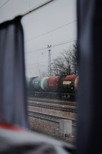View of a freight train through a window, showcasing industrial atmosphere and railway tracks.